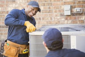 smiling-HVAC-technician-working-on-an-outdoor-AC-unit
